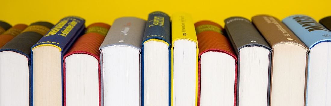 Libros de costado sobre un fondo amarillo.